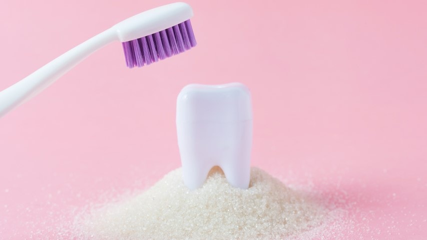 Plastic tooth in big pile of sugar.