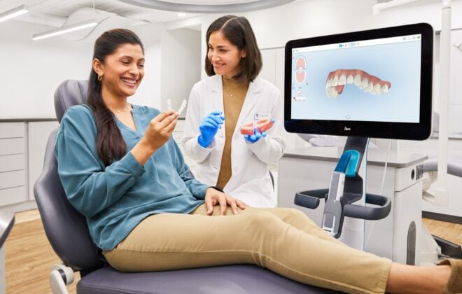 Woman in dentist chair holding Invisalign aligner.