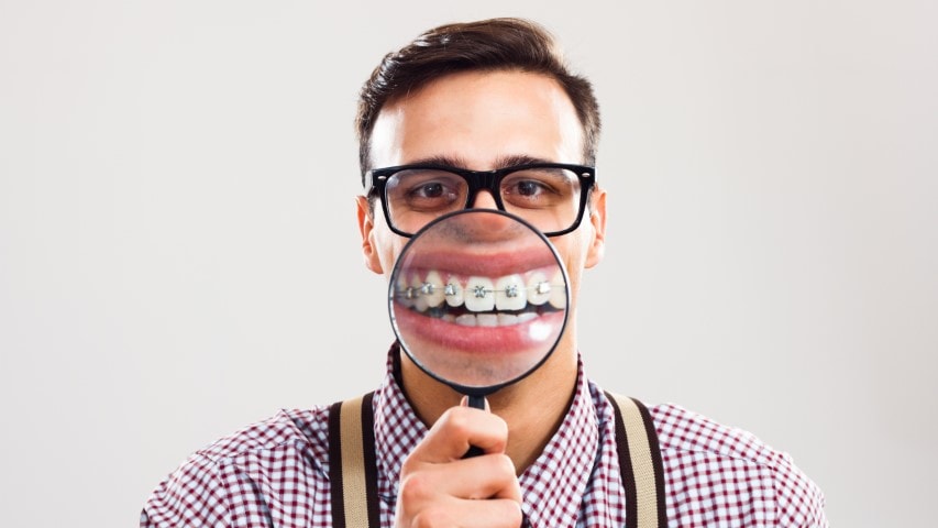 Man with braces and magnifying glass.