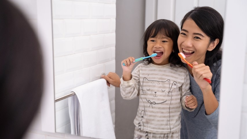 mom and kid brushing their teeth together